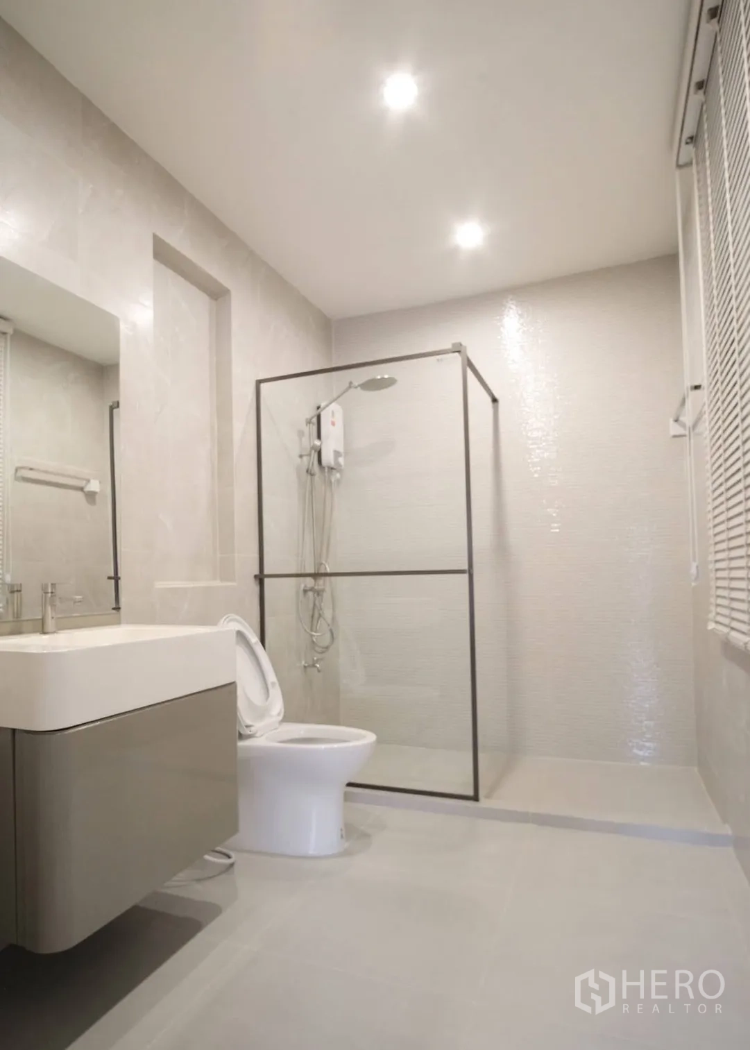 Townhouse for rent in Bang Phli, Samut Prakan - Bright modern bathroom with glass shower enclosure, wall-mounted vanity, and toilet.