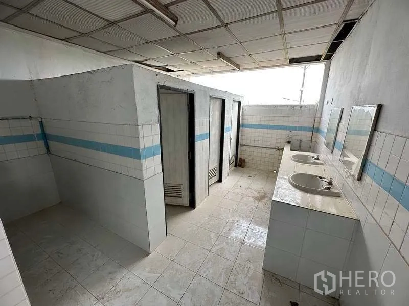 工厂 出租在Sai Noi, Nonthaburi - 员工卫生间，瓷砖墙面，分隔间与双洗手盆。