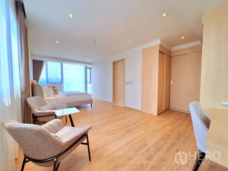 อพาร์ทเมนท์ ให้เช่าในBang Na, Bangkok - มุมพักผ่อนในห้องนอน เก้าอี้สองตัว โต๊ะทำงาน และหน้าต่างบานกว้างพร้อมผ้าม่าน