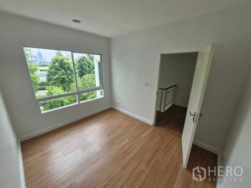 独立式住宅 出售在Rat Burana, Bangkok - 卧室转角窗，绿树景观与木地板