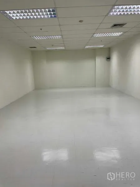 办公空间 出租在Watthana, Bangkok - 开放式白色办公室，亮面地砖、吊顶网格与明亮荧光灯。