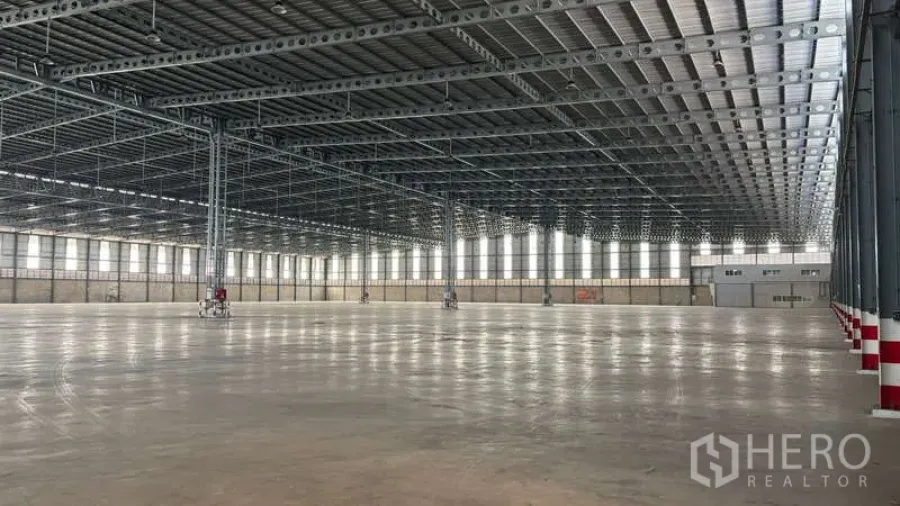 Warehouse for rent in Bang Phli, Samut Prakan - Expansive warehouse interior with high steel truss roof, polished concrete floor, and rows of clerestory windows.