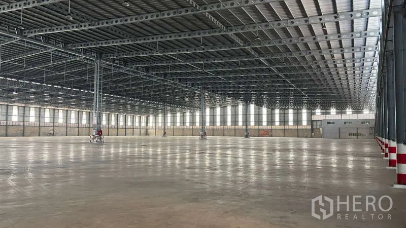 Warehouse for rent in Bang Phli, Samut Prakan - Expansive warehouse interior with high steel truss roof, polished concrete floor, and rows of clerestory windows.