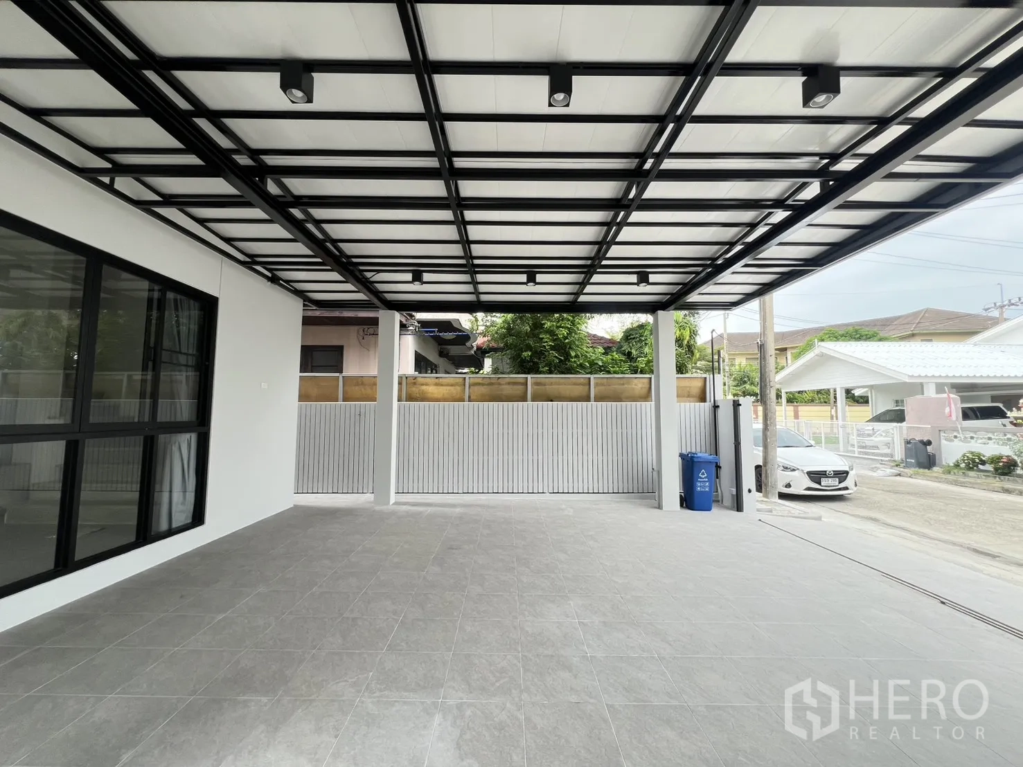 Detached House for rent in Saphan Sung, Bangkok - Front garden with palm trees beside privacy fence viewed from carport.