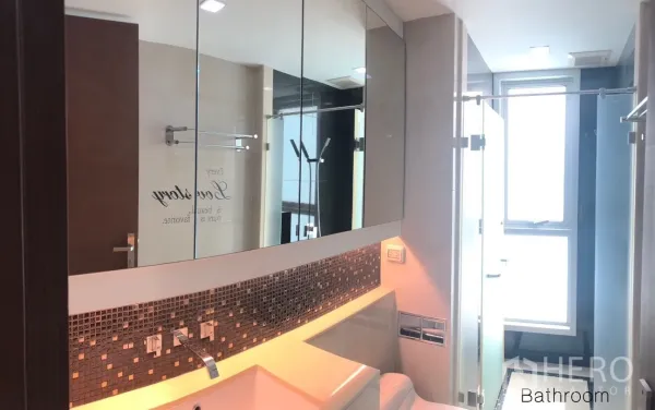 Condominium for rent or sale in Ratchathewi, Bangkok - Contemporary bathroom with mirrored cabinets, mosaic backsplash, glass partition and bright window light.