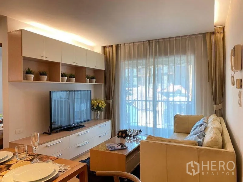 คอนโด ให้เช่าหรือขายในPhra Khanong, Bangkok - ห้องนั่งเล่นสว่างด้วยโซฟา ชั้นวางทีวี และประตูกระจกออกสู่ระเบียง