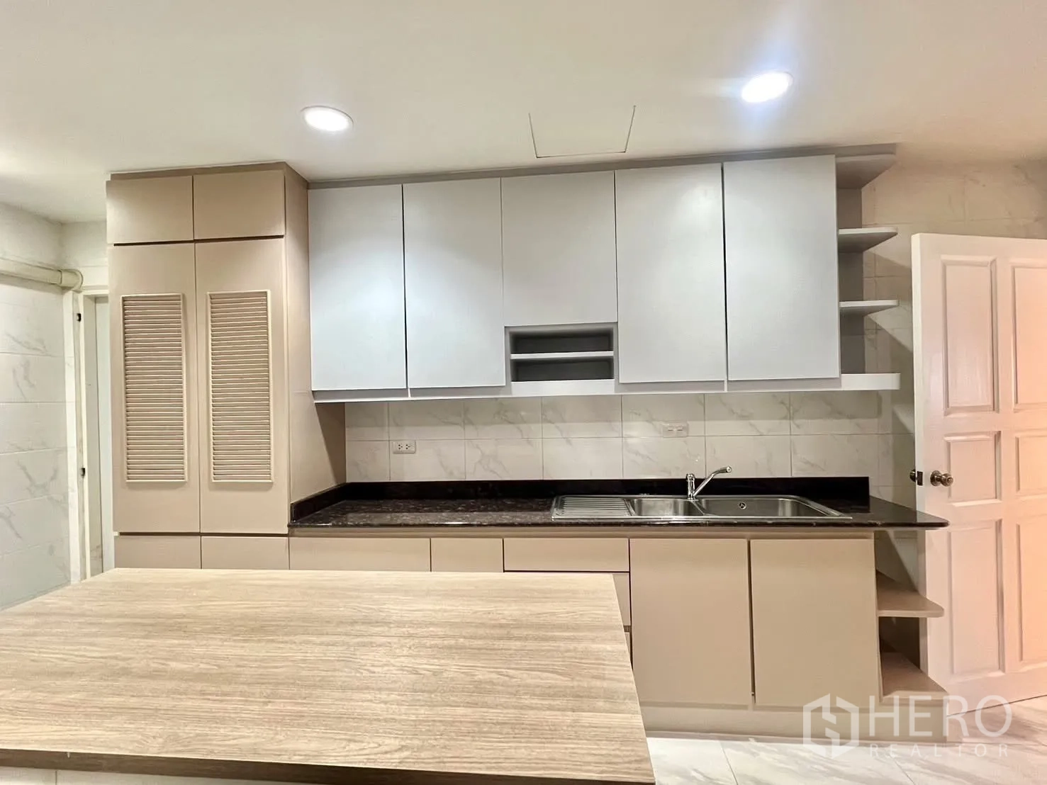 Condominium for rent in Khlong Toei, Bangkok - Kitchen wall with sink, ample cabinets and center island.