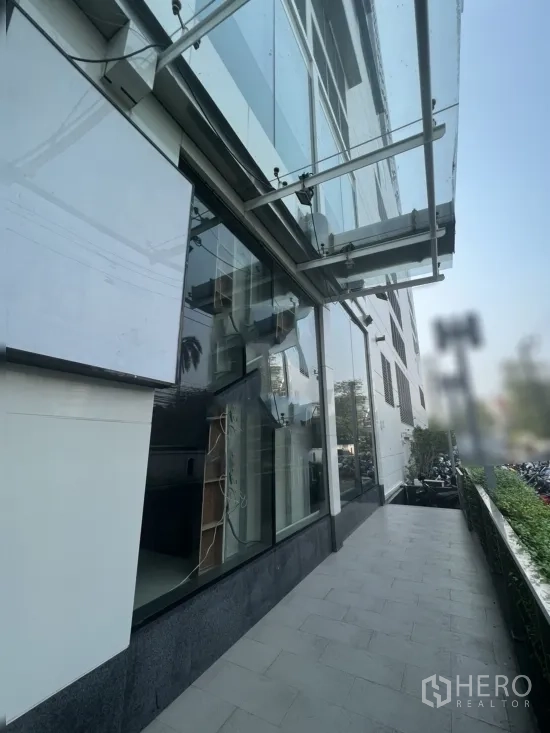 零售空间 出租在Watthana, Bangkok - 临街零售铺面，整面落地玻璃外墙与遮雨棚，旁有宽阔人行道。