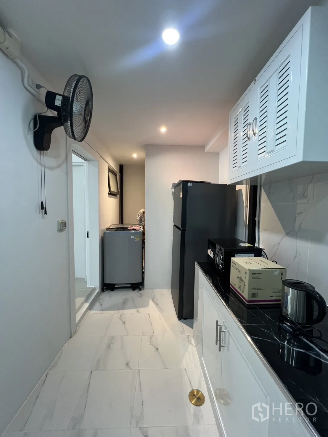 Townhouse for rent in Bang Phli, Samut Prakan - Galley kitchen with black countertop, refrigerator and washing machine.