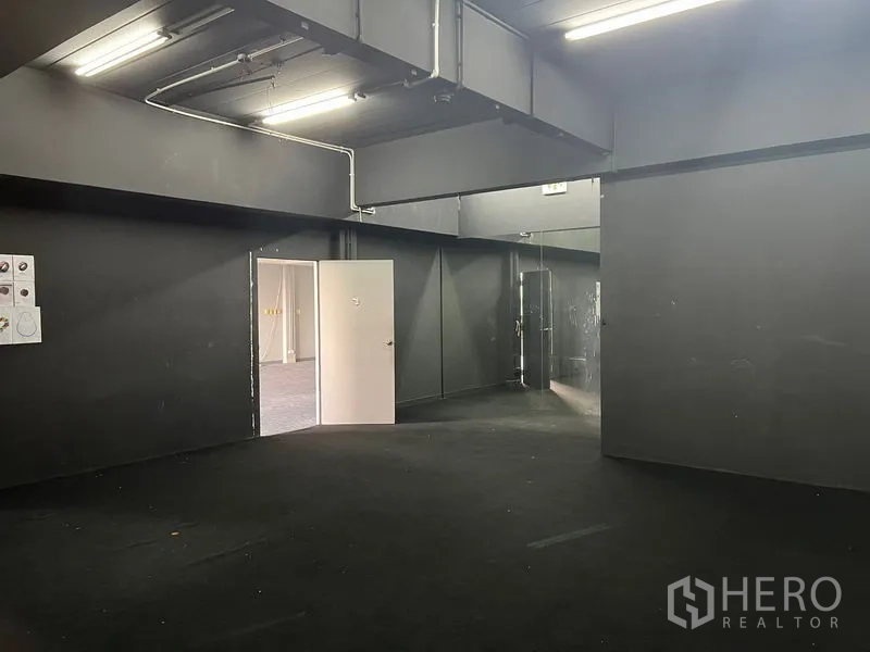 Office Space for rent in Mueang Samut Prakan, Samut Prakan - Dark studio-style room with black walls, ducting and fluorescent lights.