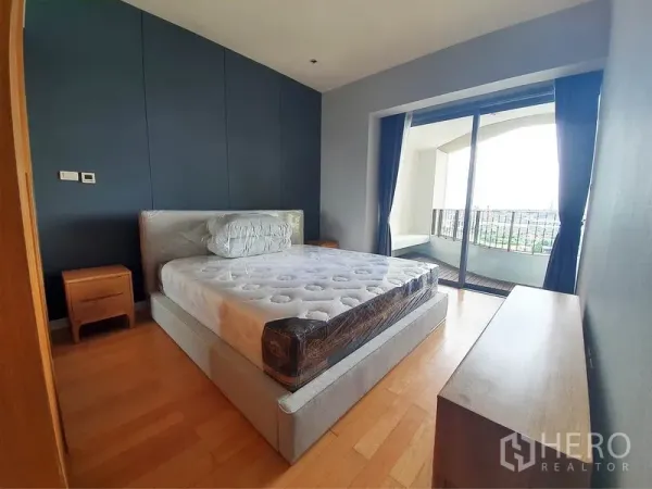 Condominium for rent in Yan Nawa, Bangkok - Master bedroom with double bed, wood flooring and sliding doors to a river-view balcony.