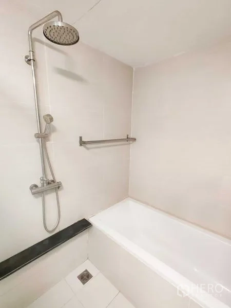 คอนโด ให้เช่าในKhlong Toei, Bangkok - อ่างอาบน้ำสีขาวพร้อมฝักบัวเรนชาวเวอร์และราวแขวนผ้าในห้องน้ำปูกระเบื้อง