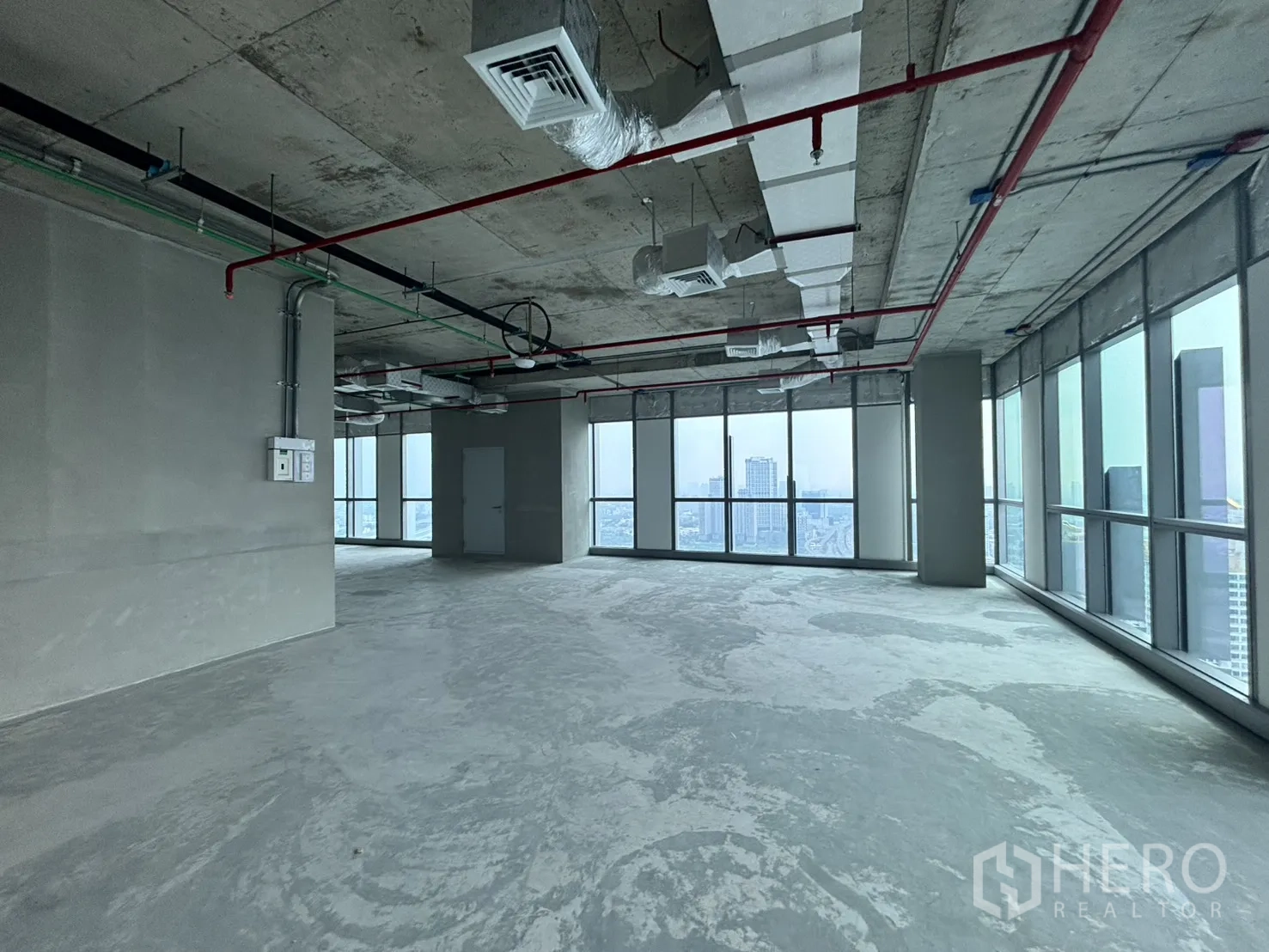 Office Space for rent in Huai Khwang, Bangkok - Shell office floor with exposed ceiling services and full-height windows overlooking the city.