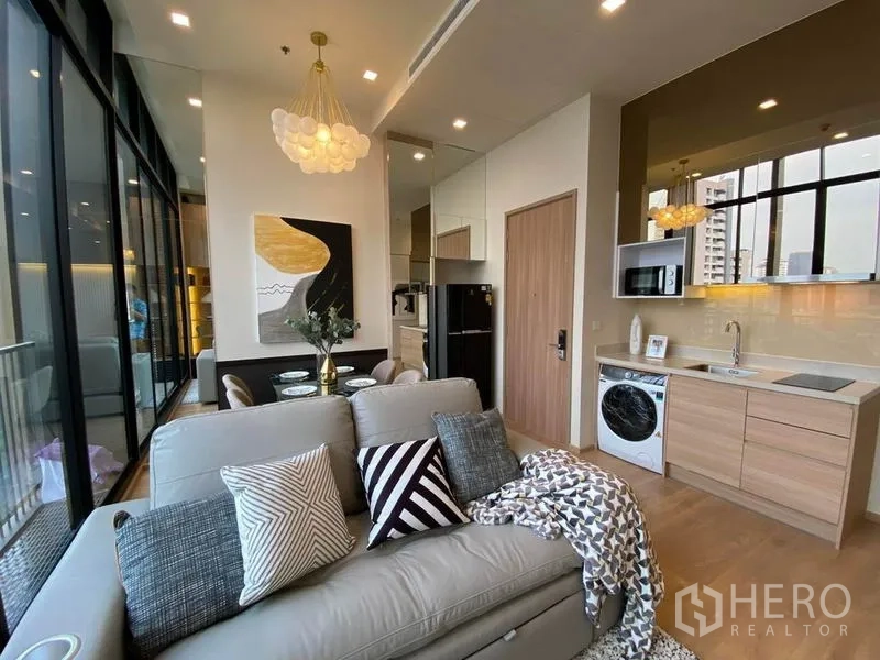 คอนโด ให้เช่าในWatthana, Bangkok - ห้องนั่งเล่นพร้อมโซฟา ชุดทานอาหาร และครัวขนาดกะทัดรัดรับหน้าต่างสูง