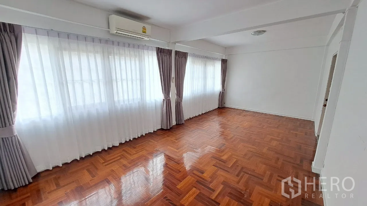 Townhouse for rent in Watthana, Bangkok - Large bedroom with air conditioner, long curtained windows and parquet floor.