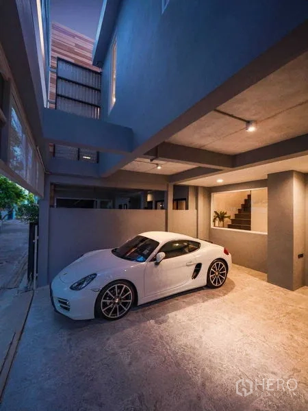 ทาวน์เฮาส์ ให้เช่าในWatthana, Bangkok - ที่จอดรถในร่มหน้าบ้านพร้อมไฟเพดานและรถสปอร์ตสีขาว