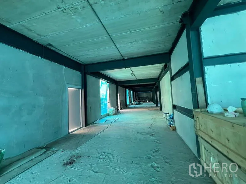 零售空间 出租在Pathum Wan, Bangkok - 长形走廊空间，未完成墙面，侧窗与零星施工工具可见。