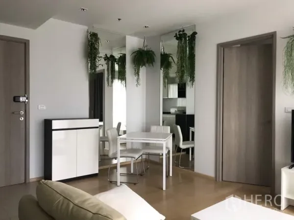 Condominium for rent in Watthana, Bangkok - Bright dining corner with white table, mirrored walls, and hanging greenery in a modern condo.