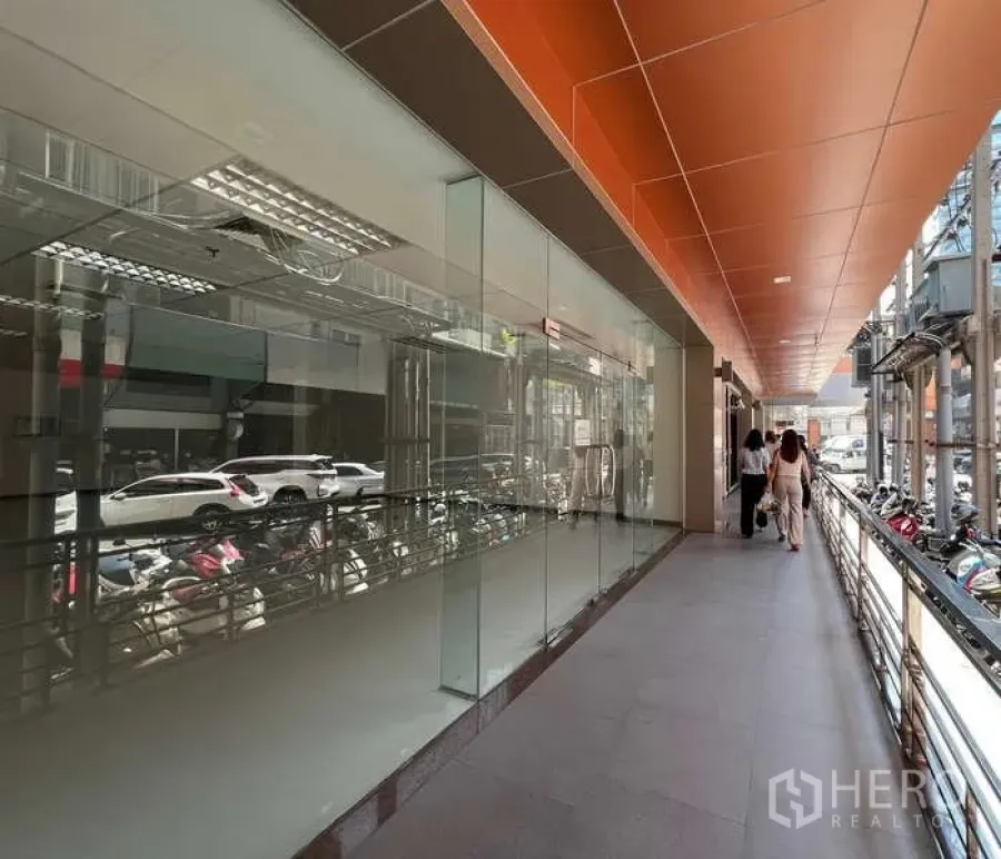 零售空间 出租在Pathum Wan, Bangkok - 有顶走道旁的玻璃店面与橙色天花板，位于曼谷市中心。
