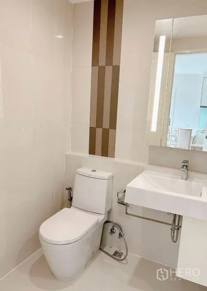 Condominium for rent in Watthana, Bangkok - Clean guest bathroom with toilet, floating sink and vertical tile feature.