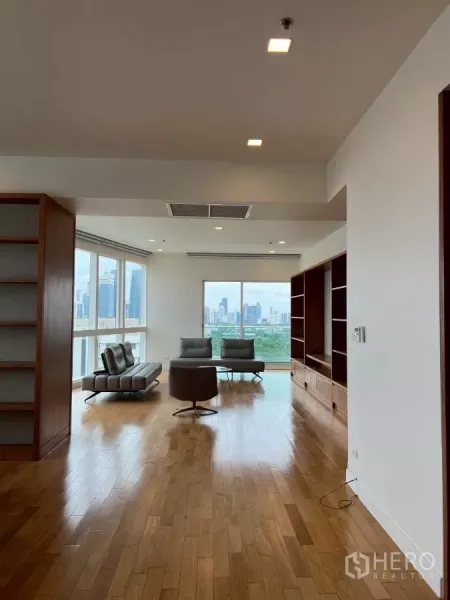 คอนโด ให้เช่าในKhlong Toei, Bangkok - ห้องนั่งเล่นสว่าง พื้นไม้จริง ชั้นวางบิลท์อิน และกระจกบานใหญ่ชมวิวสกายไลน์และสวนกรุงเทพฯ
