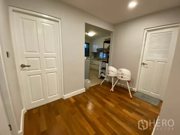 คอนโด ให้เช่าหรือขายในWatthana, Bangkok - โถงทางเข้าพร้อมประตูบานลูกฟักสีขาว เชื่อมไปครัวแยก พื้นไม้