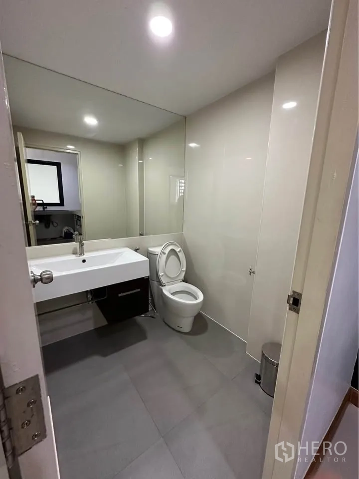 Townhouse for rent in Pak Kret, Nonthaburi - Modern bathroom with large mirror, sink vanity, and toilet.