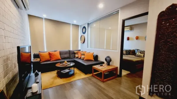 公寓 出售在Watthana, Bangkok - 客厅配L型皮沙发、电视柜与柔和氛围灯光。