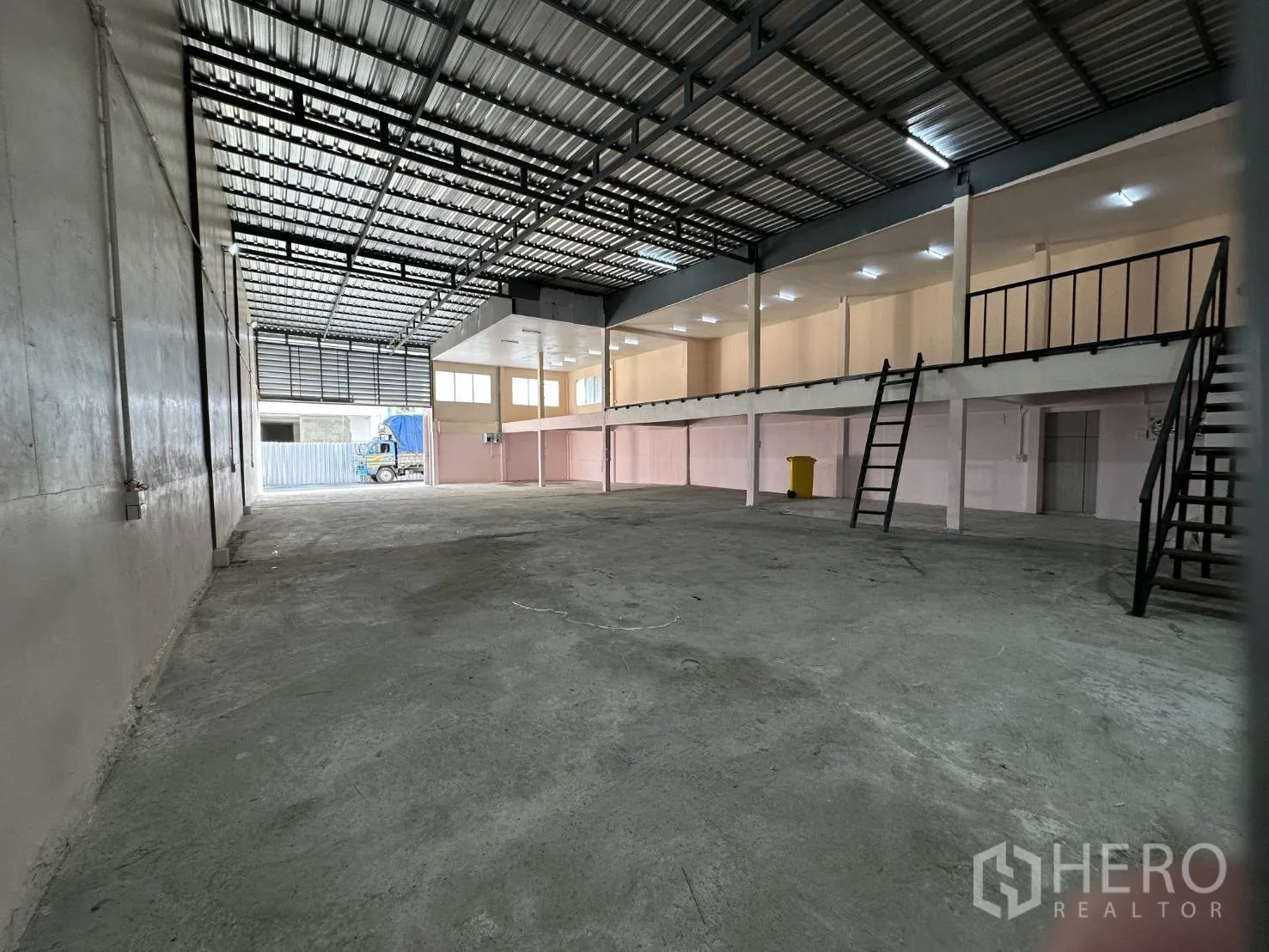 Warehouse for rent in Din Daeng, Bangkok - Spacious warehouse interior with high steel roof, open concrete floor, mezzanine rooms and twin staircases.