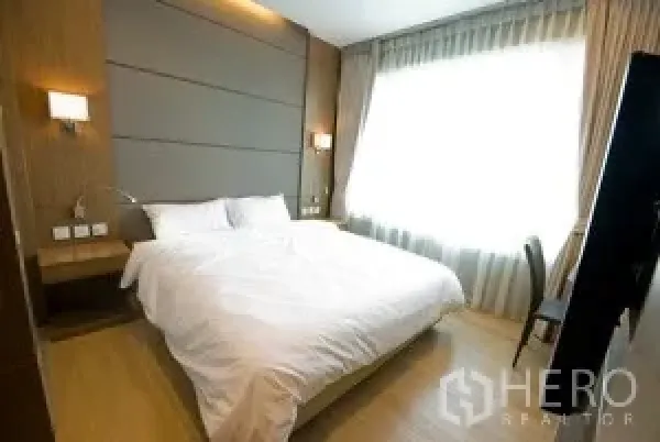 คอนโด ให้เช่าในKhlong Toei, Bangkok - ห้องนอนหลักเตียงคิง หัวเตียงบุผ้า โคมไฟข้างเตียง และหน้าต่างขนาดใหญ่พร้อมผ้าม่าน