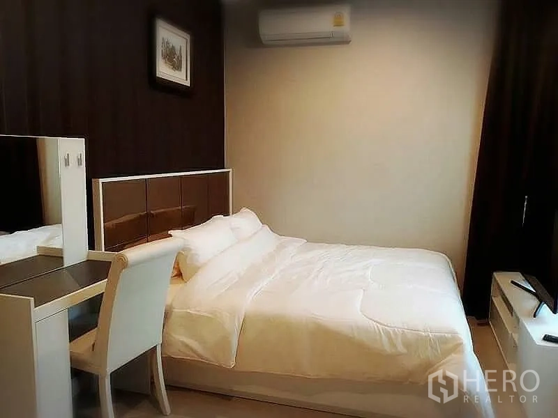 Condominium for rent or sale in Huai Khwang, Bangkok - Master bedroom with padded headboard, vanity desk and air conditioning.