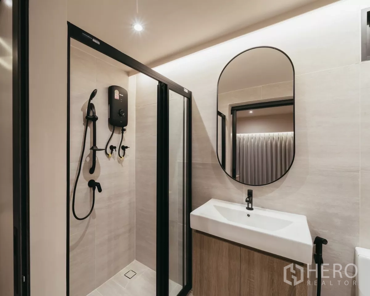 联排别墅 出租在Watthana, Bangkok - 浴室带玻璃淋浴房、椭圆镜与木质洗手台。