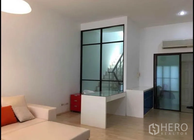 Townhouse for sale in Khlong Toei, Bangkok - Open-plan living space with glass-walled staircase, work desk and sliding door.