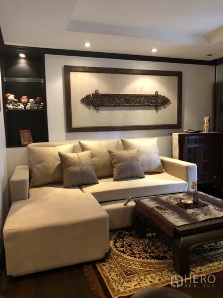 คอนโด ให้เช่าในWatthana, Bangkok - ห้องนั่งเล่นอบอุ่น โซฟาเข้ามุม งานตกแต่งผนัง และโต๊ะกาแฟไม้