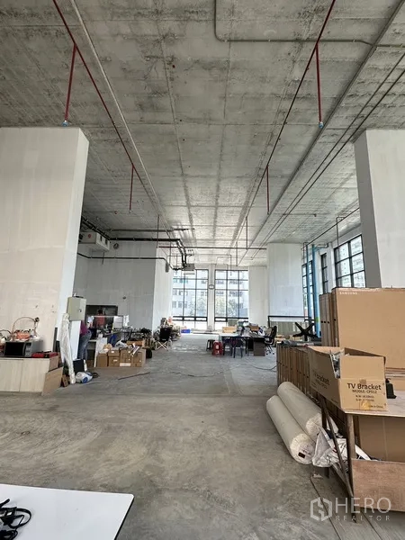 Retail Space for rent in Khlong Toei, Bangkok - Spacious bare-shell retail interior with double-height ceiling, exposed services, and large windows filling the space with natural light.