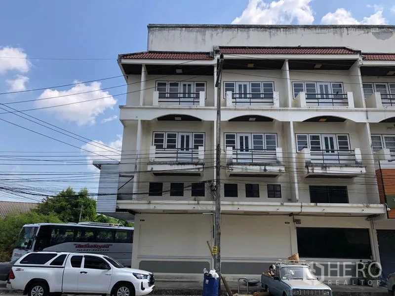 Shophouse for sale in Lam Luk Ka, Pathum Thani - Four-storey shophouse facade with balconies and a wide ground-floor frontage on a busy street.