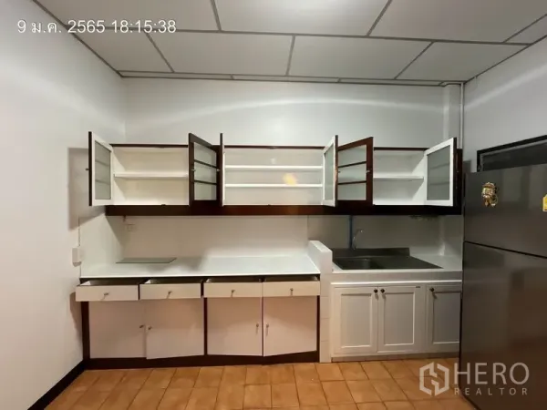 บ้าน ให้เช่าในKhlong Toei, Bangkok - ห้องครัวสว่างพร้อมท็อปสีขาว ตู้กระจกเปิดอยู่ และอ่างล้างจานสแตนเลส