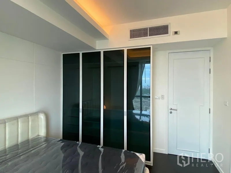 Condominium for rent - Bedroom wall with black glass wardrobe doors.