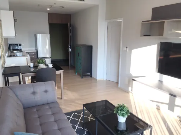 公寓 出租在Bangkok - 开放式客厅，配沙发、电视、餐桌与紧凑厨房