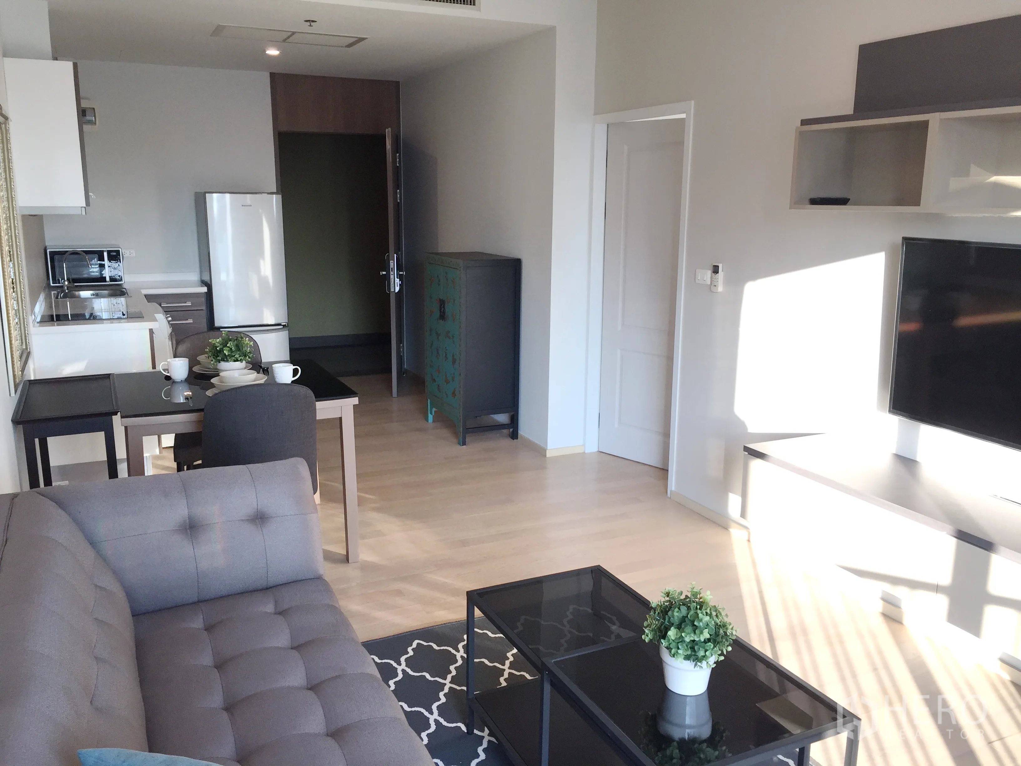 公寓 出租在Bangkok - 开放式客厅，配沙发、电视、餐桌与紧凑厨房