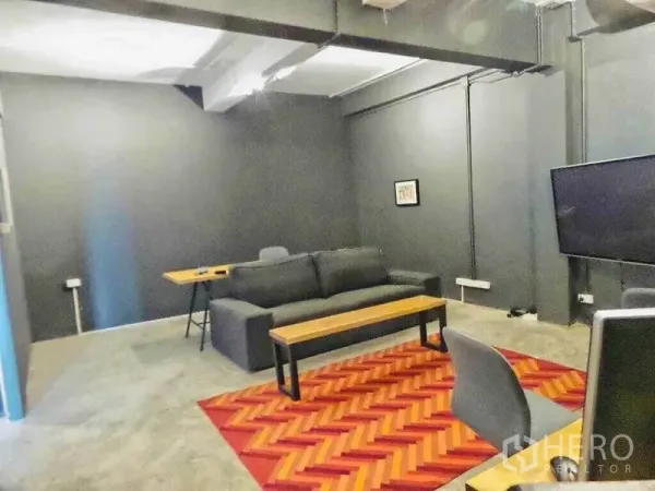 带办公室的家 出租或出售在Din Daeng, Bangkok - 工业风会客区，深色墙面，沙发、电视与红色纹理地毯。