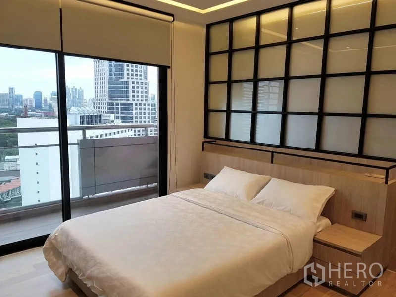 Condominium for rent in Bang Rak, Bangkok - Bright bedroom with double bed, grid headboard and sliding doors to a city-view balcony.