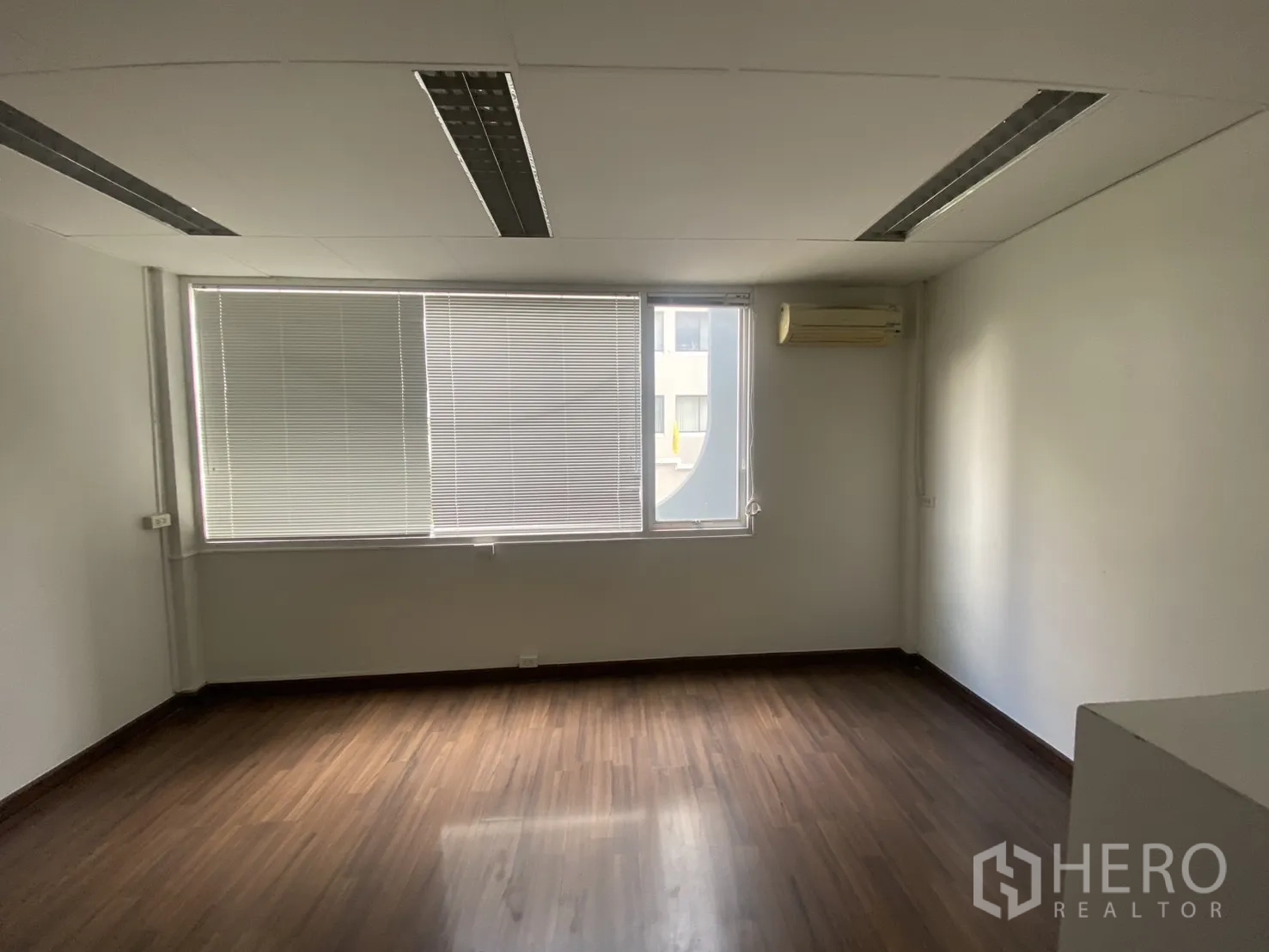 Shophouse for rent in Bang Rak, Bangkok - Office room with large window blinds, wall air-conditioner, and wood-look floor.