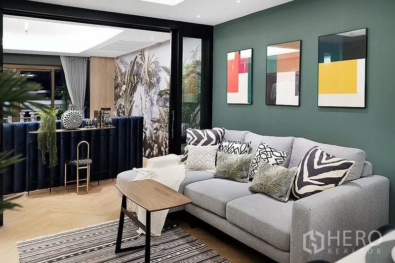 公寓 出租在Bang Rak, Bangkok - 时尚客厅，灰色沙发与装饰画，推拉玻璃门通向吧台区和阳台。