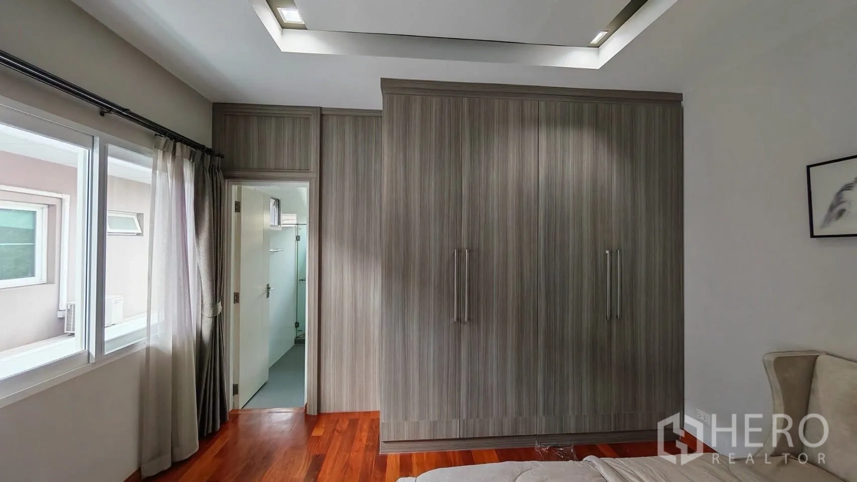 Detached House for rent or sale in Bang Phli, Samut Prakan - Bedroom corner with floor-to-ceiling wardrobe and a doorway leading to the bathroom.