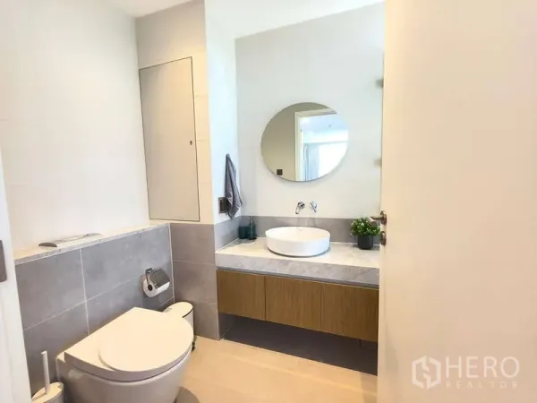 อพาร์ทเมนท์ ให้เช่า - ห้องน้ำสว่างที่โฮล์ม เอกมัย 22 มีกระจกกลม อ่างล้างหน้าแบบวาง และโถสุขภัณฑ์แขวนผนัง