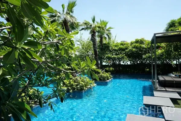 Condominium for rent or sale in Ratchathewi, Bangkok - Resort-style swimming pool surrounded by lush greenery and a shaded cabana.