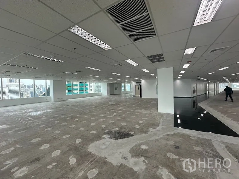 Office Space for rent - Bright office zone with slanted exterior glazing and multiple windows facing high‑rises.
