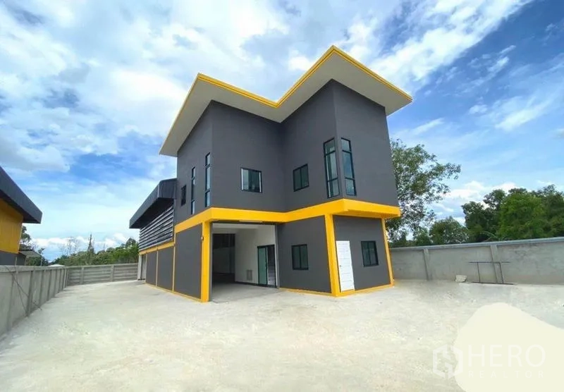 Warehouse for rent in Lat Lum Kaeo, Pathum Thani - Modern two-storey warehouse with gray facade, yellow trim and a large driveway.