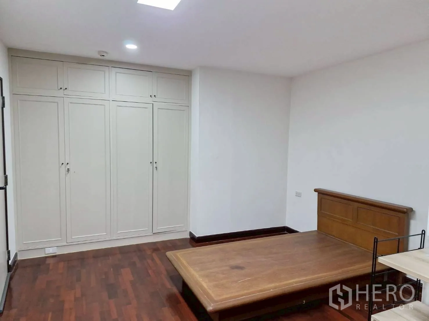 Condominium for rent in Khlong Toei, Bangkok - Bedroom with wooden bed frame, built-in wardrobes and hardwood flooring.